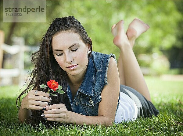 Attraktives multiethnisches Mädchen Tagträumen liegend im Gras im Freien mit Blume