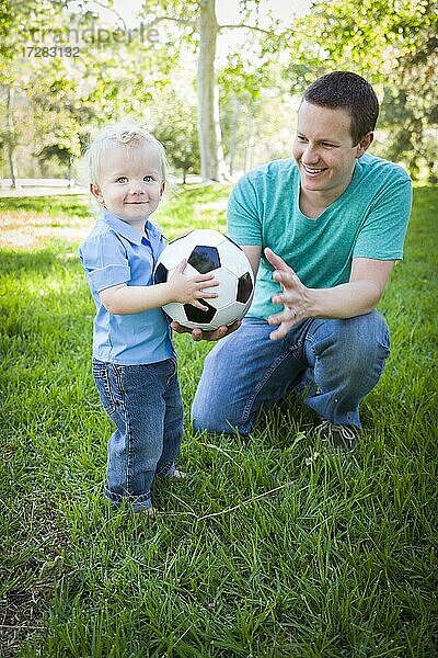 Junge niedlichen Jungen und Papa spielen mit Fußball im Park