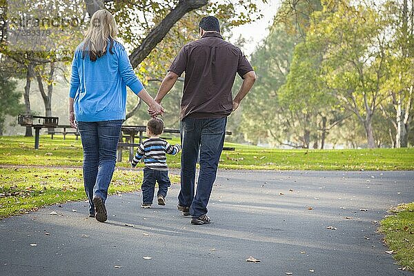 Glückliche junge gemischtrassige ethnische Familie beim Spaziergang im Park