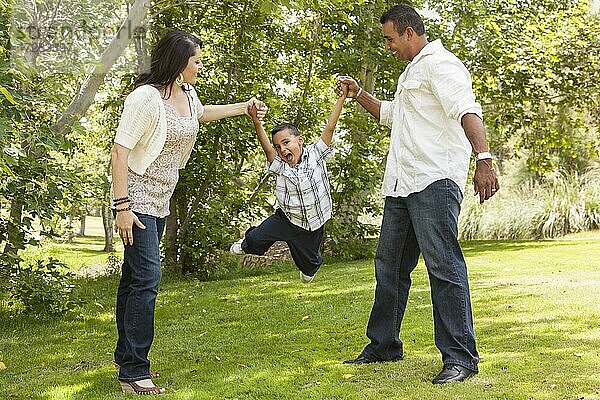 Glückliche hispanische Mutter und Vater schwingen Sohn im Park