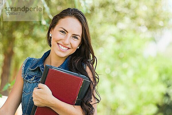 Attraktive lächelnde gemischtrassige junge Mädchen Studentin mit Schule Bücher im Freien