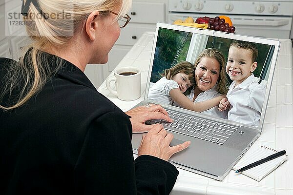 Frau in der Küche mit Laptop sehen Freunde und Familie. Bildschirm kann leicht für Ihre eigene Nachricht oder Bild verwendet werden