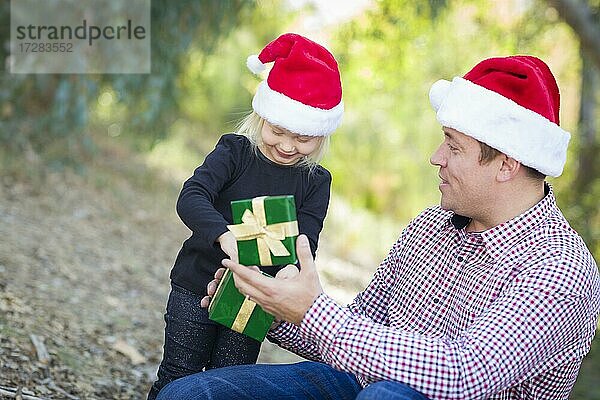 Glücklicher Vater gibt junge Tochter ein Weihnachtsgeschenk im Freien