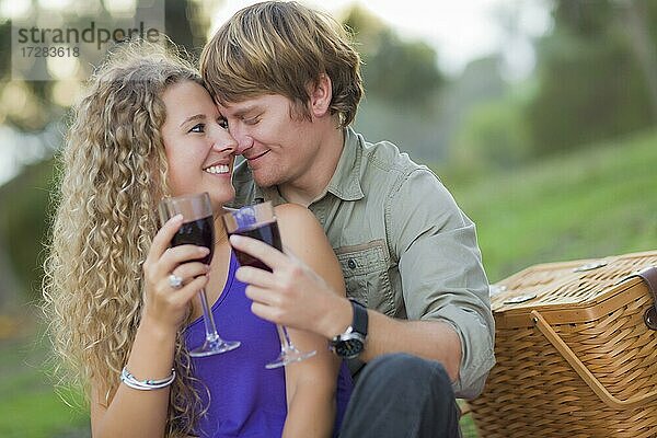 Ein attraktives Paar  das gemeinsam ein Glas Wein im Park genießt