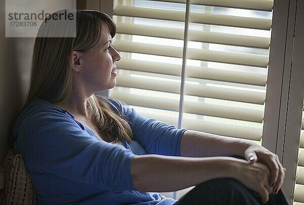 Pensive Frau ruhig sitzen in der Nähe von Fenster Jalousien