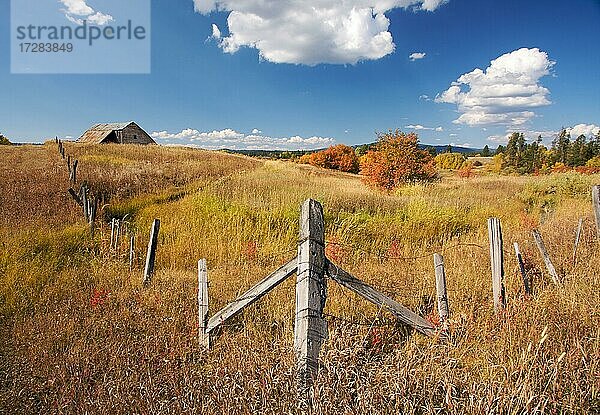 Schöne Herbstlandschaft mit rustikaler Scheune  Zaun und Wolken