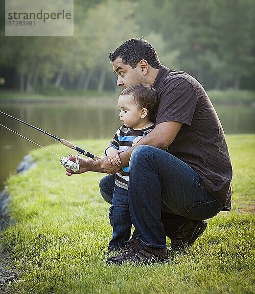 Glückliche junge ethnische Vater und Sohn Angeln am See
