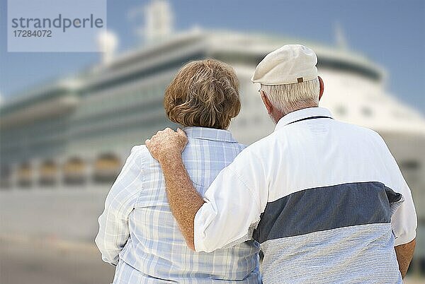 Älteres Paar an Land mit Blick auf ein angedocktes Kreuzfahrtschiff