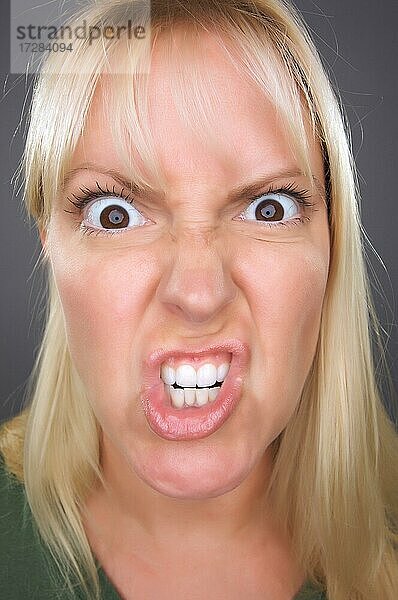 Wütende blonde Frau vor einem grauen Hintergrund