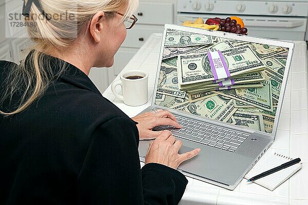 Frau in der Küche mit Laptop  um Geld zu verdienen oder zu gewinnen. Bildschirm kann leicht für Ihre eigene Nachricht oder Bild verwendet werden