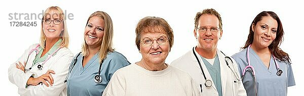 Lächelnde ältere Frau mit Ärzten und Krankenschwestern hinter vor einem weißen Hintergrund
