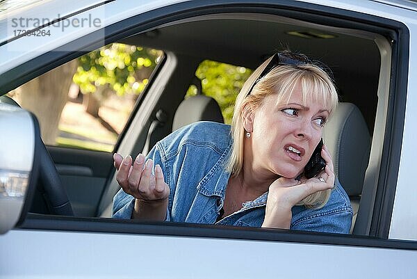 Besorgte blonde Frau  die während der Fahrt ein Mobiltelefon benutzt
