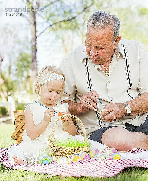 Liebevolle Großvater und Enkelin Färbung Ostereier zusammen auf Picknick-Decke im Park