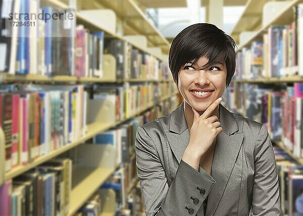 Neugieriges gemischtrassiges Mädchen  das in der Bibliothek zur Seite schaut
