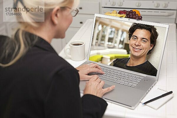 Glückliche junge Frau in der Küche mit Laptop Online-Dating-Suche mit Porträt von Mann auf dem Bildschirm