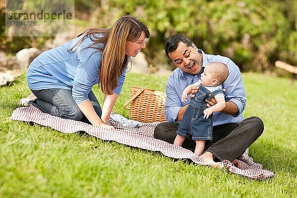 Glückliche gemischtrassige Familie  die ein Picknick macht und im Park spielt