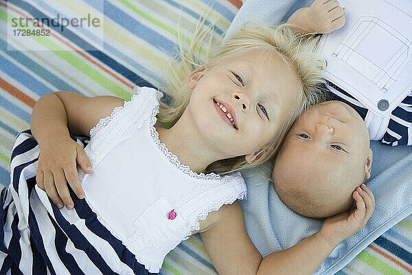 Niedliche kleine Schwester liegt neben ihrem kleinen Bruder auf der Decke