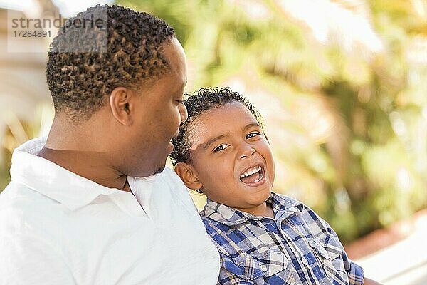 Glücklicher afrikanischer amerikanischer Vater und gemischtrassiger Sohn im Gespräch im Park