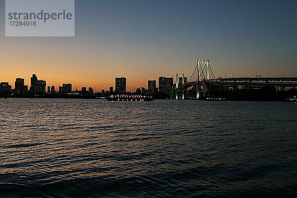 Blick vom Odaiba Beach auf die Bucht von Tokio mit Regenbogenbrücke in der Abenddämmerung  Tokio  Japan  Asien