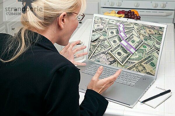 Aufgeregte Frau in der Küche mit Laptop  um Geld zu verdienen oder zu gewinnen. Bildschirm kann leicht für Ihre eigene Nachricht oder Bild verwendet werden