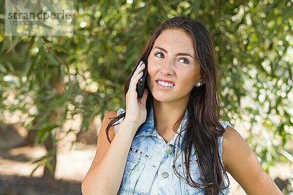 Unglückliche  verwirrte gemischtrassige junge Frau  die draußen mit einem Handy telefoniert