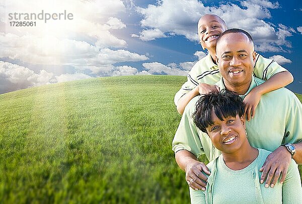Glückliche afroamerikanische Familie über Wolken  Himmel und gewölbten Horizont von Grasfeld