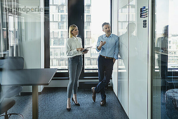Männlicher Fachmann  der mit einer weiblichen Kollegin über eine weiße Tafel diskutiert  während er eine Strategie im Büro plant