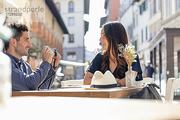 Männlicher Tourist fotografiert Frau in einem Straßencafé durch die Kamera