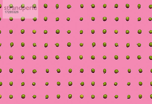 Muster von grünen Erbsen flach auf rosa Hintergrund gelegt