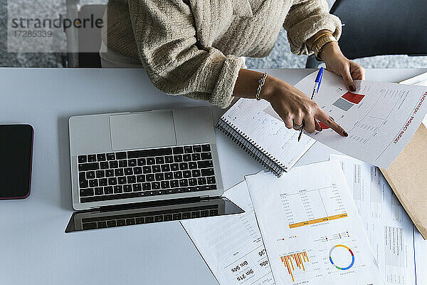 Unternehmerin analysiert Daten  während sie im Büro vor einem Laptop sitzt