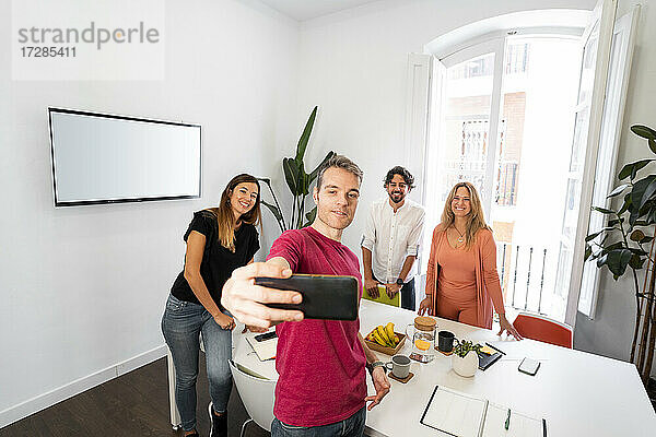 Männlicher Unternehmer macht Selfie mit Kollegen im Coworking-Büro