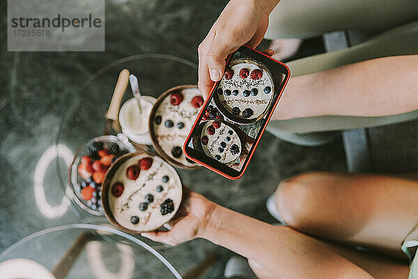 Mädchen fotografiert Obstschalen mit dem Smartphone