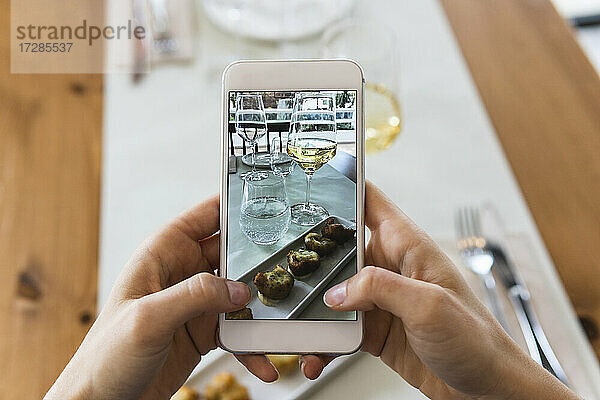 Junge Frau fotografiert Essen mit ihrem Smartphone in einem Restaurant