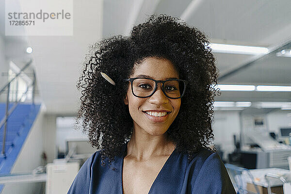 Lächelnde Geschäftsfrau mit krausem Haar in der Industrie