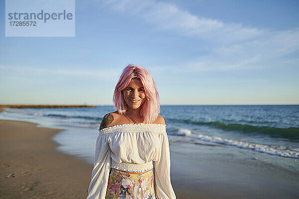 Lächelnde Hipster-Frau am Strand stehend an einem sonnigen Tag