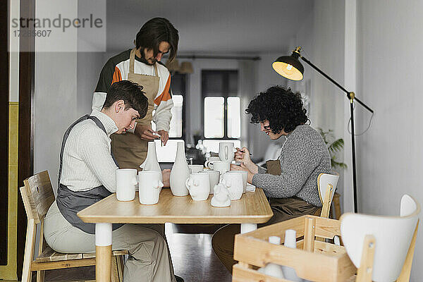 Männliche und weibliche Experten bemalen Keramikgeschirr am Arbeitsplatz