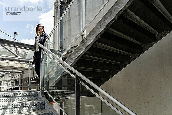 Unternehmerin schaut weg  während sie in der Nähe eines Geländers in einem Gebäude steht