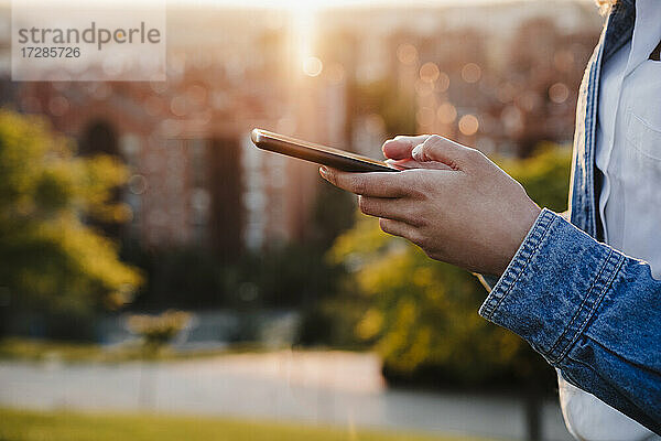 Frau benutzt Smartphone bei Sonnenuntergang