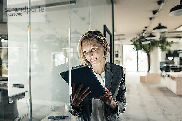 Lächelnde Geschäftsfrau mit digitalem Tablet im Büro