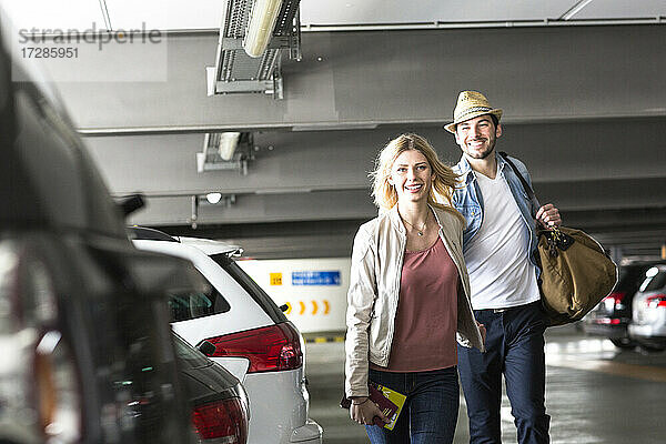 Junges Paar geht über einen Flughafenparkplatz