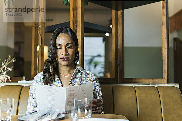 Junge Frau liest Speisekarte im Restaurant