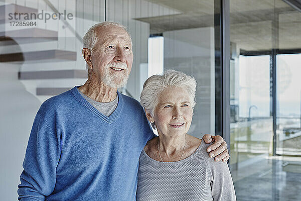 Lächelndes älteres Paar  das zusammen vor einer Glaswand steht