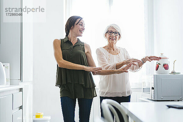 Glückliche Frau mit Großmutter tanzt in der Küche