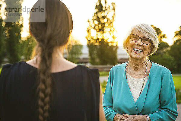Lächelnde Großmutter steht mit Enkelin im Park
