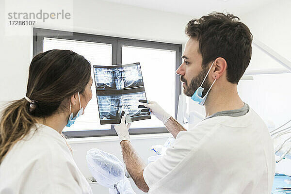 Ein männlicher Zahnarzt zeigt einer Assistentin in einer medizinischen Klinik ein Röntgenbild