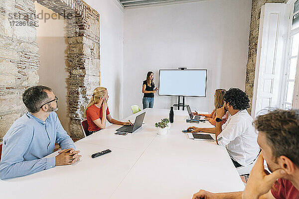 Weibliche Fachkraft  die eine Besprechung auf einer Projektionsfläche im Sitzungssaal eines Coworking-Büros leitet