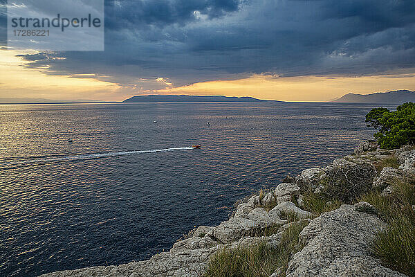 Motorboot segeln in der Nähe der Küste in Makarska Riviera bei bewölkter Abenddämmerung