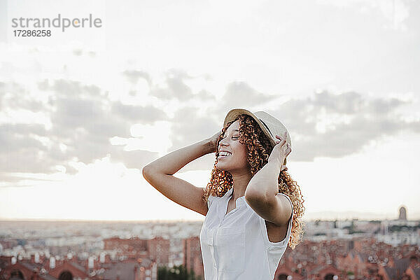 Glückliche hispanische Frau mit Hut vor dem Himmel