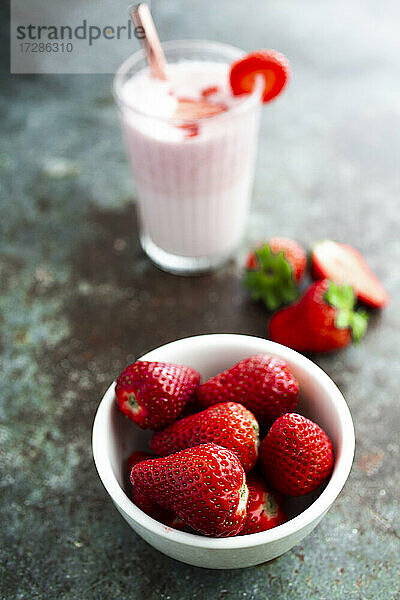 Schale mit frischen Erdbeeren und Glas Erdbeer-Smoothie