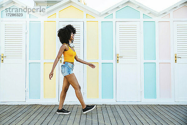 Glückliche junge Afro-Frau  die an Strandhütten vorbeiläuft